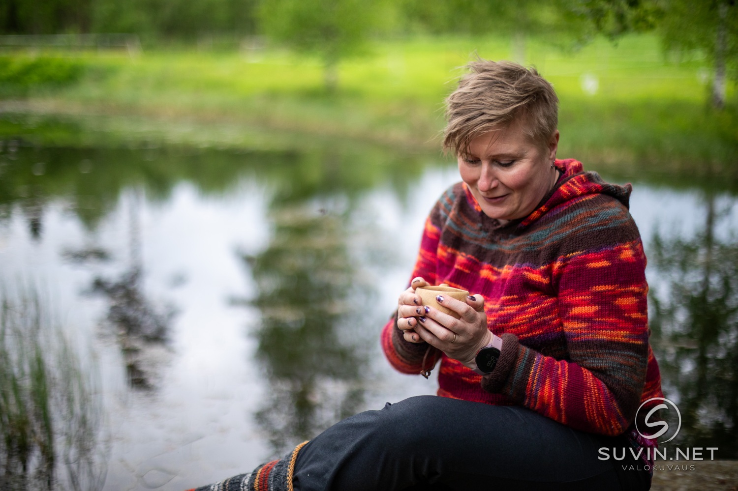 Nainen luonnossa kahvikuppi kädessään.